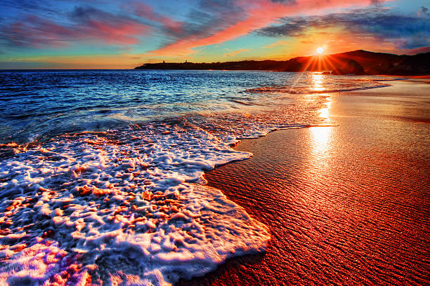 brillante vacanza alba sulla spiaggia con sabbia colorata e distante cliffs - essaouira foto e immagini stock