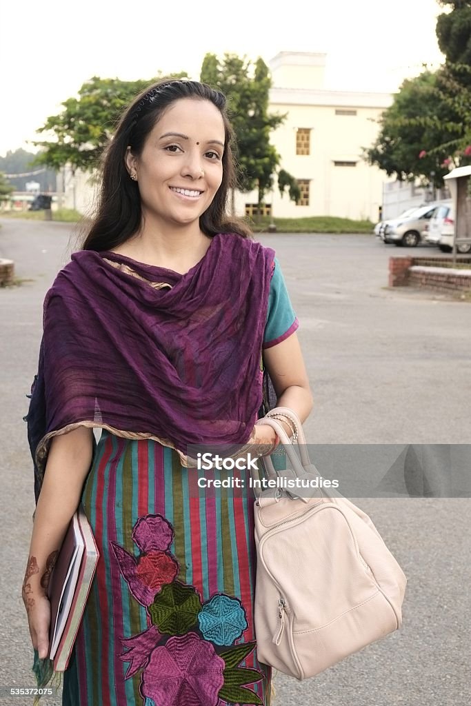 Attractive Indian female teacher walking on road. Portrait of a happy Indian professor going to college campus. 2015 Stock Photo