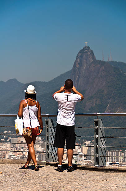 Tourists on the Sugarloaf Mountain watching Corcovado Rio de Janeiro, Brazil - January 18, 2015: A couple watching and photographing Corcovado and Christ the Redeemer from the Sugarloaf Mountain. Corcovado and Sugarloaf are main attractions of the city. corcovado stock pictures, royalty-free photos & images