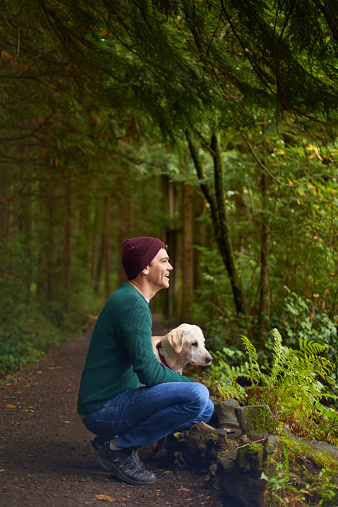 Shot of a young man and his dog in a lush forest