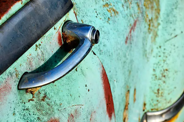 A close up image of the door handle of an old rusted Pontiac door handle.