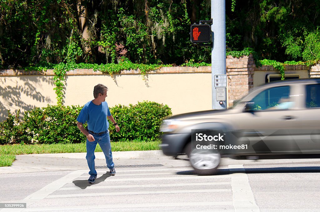 Jaywalking man about to be run over by truck A man is jaywalking across an intersection when the signal is clearly showing the do not cross symbol.  Pedestrian Stock Photo