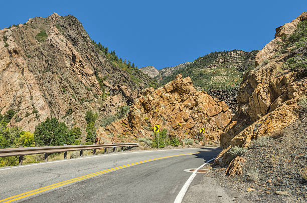 Paved Road Through the Mountains Two-lane winding road through the Wasatch Mountains in Utah with just a hint of fall here and there. single yellow line sunlight usa utah stock pictures, royalty-free photos & images