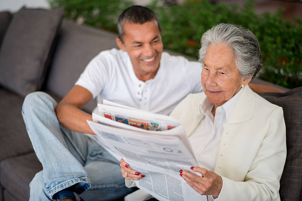 donna anziana leggendo il giornale - grandparent senior adult child reading foto e immagini stock