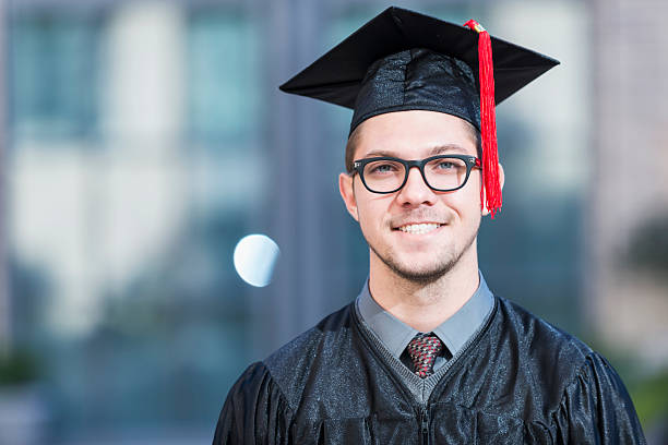 hombre joven en traje de graduación y la tapa - poses para fotos de graduación fotografías e imágenes de stock
