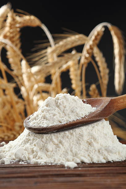 istock Wheat flour on wooden spoon at wheat ears background 535402588