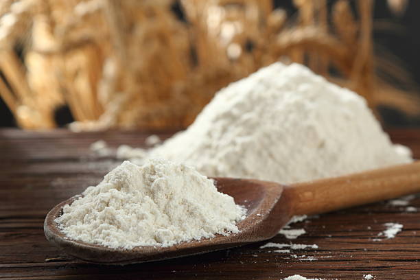 istock Wheat flour on wooden spoon at wheat ears background 535402618