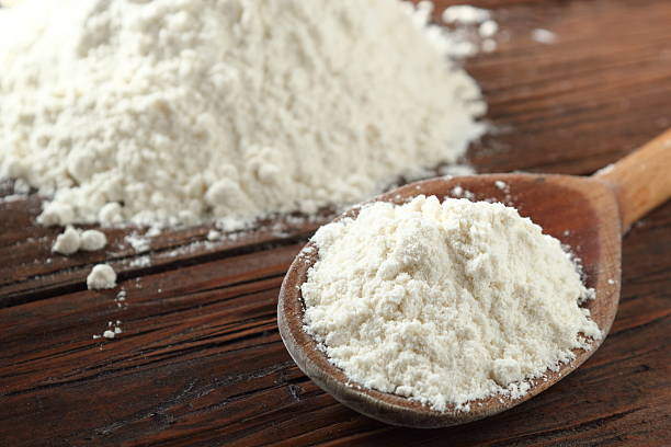 istock Wooden spoon with wheat flour on plank table 535402692