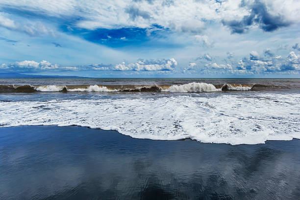 Black sand, waves and sky on the beach Bali stock photo