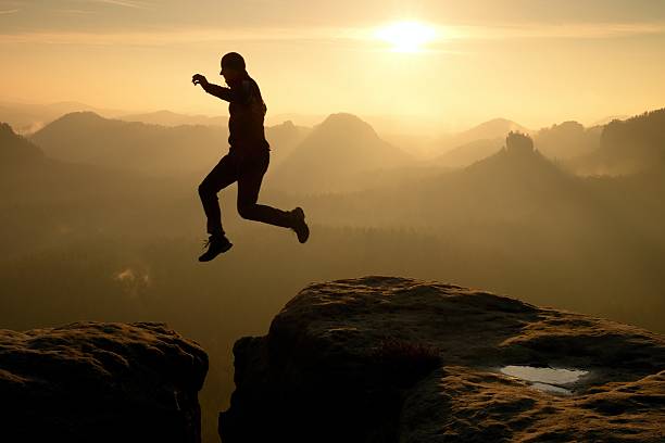 istock Crazy hiker jump between cliffs. Amazing mountains, heavy mist 535405656