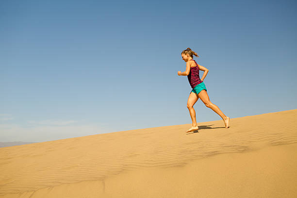 istock Young woman running on sand desert dunes 535405764