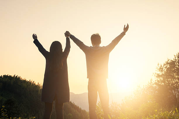 istock Couple Looking at Sunset With Their Arms Raised 535406258