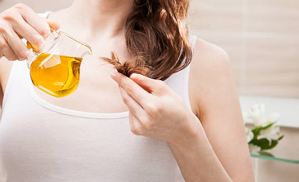 woman applying oil mask to hair tips - moisten imagens e fotografias de stock