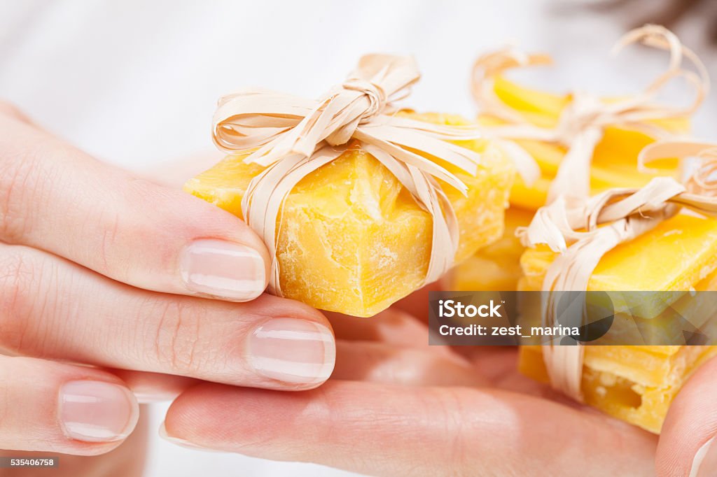 Woman hands holding pieces of beeswax Woman hands holding pieces of natural beeswax, packed and decorated Candle Stock Photo