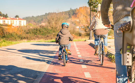 Back view of happy family with children riding bicycles by the nature on a sunny winter day