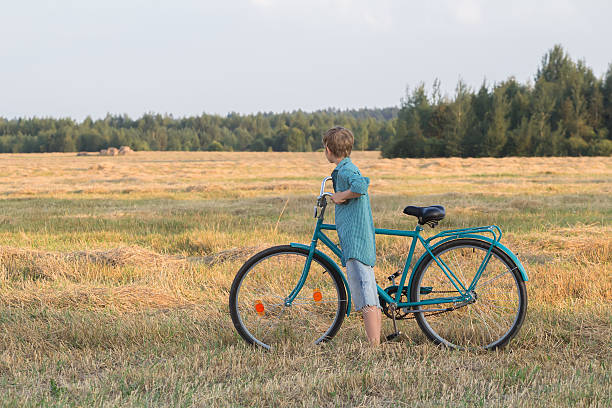 Teenager boy retención bicicleta en campo de la granja - foto de stock