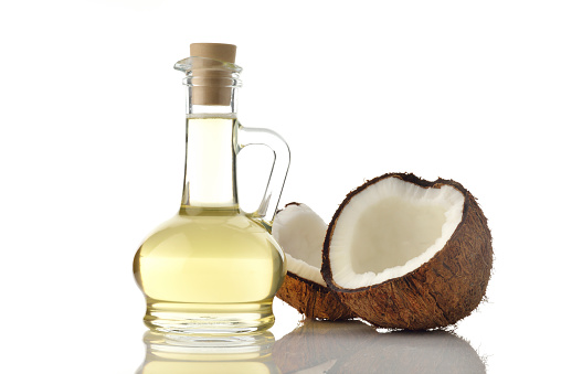 High resolution image of coconut oil decanter with coconuts on white background shot in studio