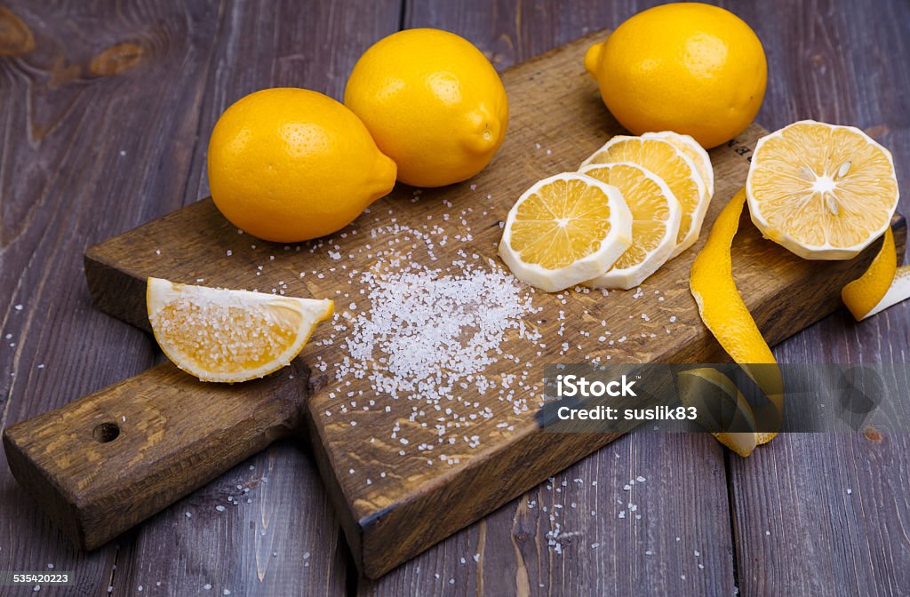 low key lemons some sliced lemons on a wooden cutting board and sea salt 2015 Stock Photo