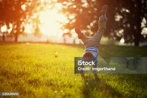 istock Little boy standing on hands on grass 535420492