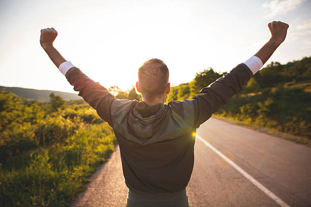 Man raising arms Sport and life achievements and success concept. Sporty man raising arms towards beautiful sunset on the road road to success stock pictures, royalty-free photos & images