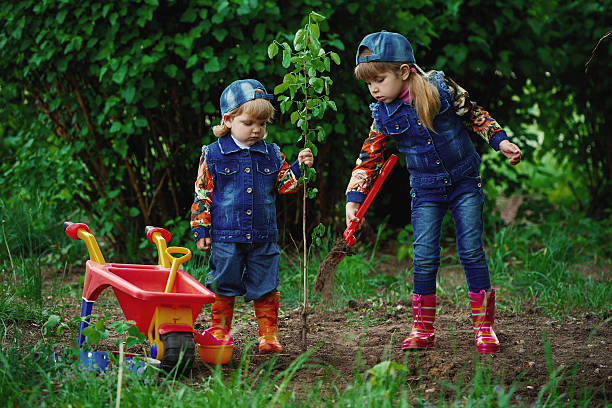 photo of little happy girls planting tree