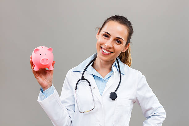 Beautiful female doctor with  piggy bank stock photo