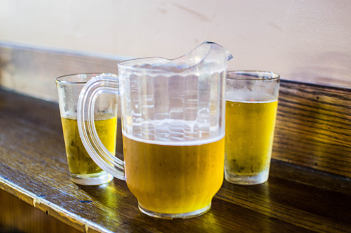 Beer poured into two cold glasses next to a pitcher.