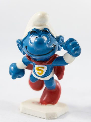 Milan, Italy - May 28th 2016: close up on a smurf plastic toy dressed as Superman, resting on a white background. Nothing else is visible in the frame.