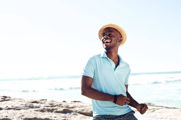 cheerful young african man enjoying at the beach - men's fashion stockfoto's en -beelden