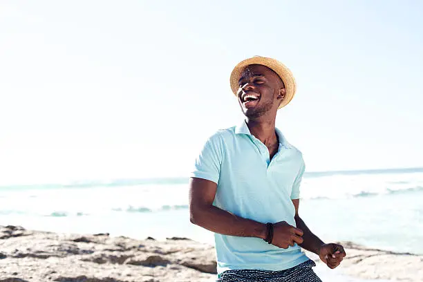 Photo of Cheerful young african man enjoying at the beach