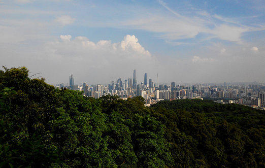 Guangzhou, China - August 1st, 2015: general view of Guangzhou downtown skyscrapers and main part of the city emerging from the trees on the top of Baiyun viewpoint on a cloudy but not polluted day in the south of China.