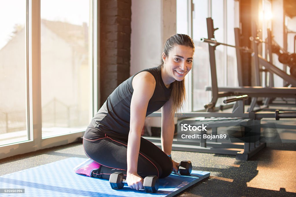 Mujer joven haciendo ejercicios con pesas en el gimnasio. - Foto de stock de Actividad libre de derechos
