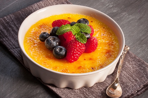  gorgeous French dessert Creme brulee served with berries and a silver spoon