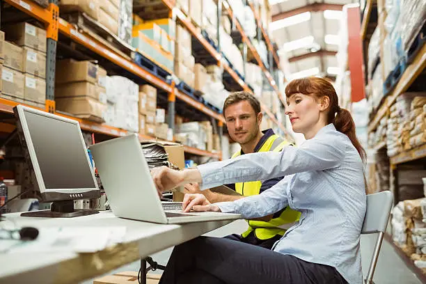 Photo of Warehouse worker and manager looking at laptop