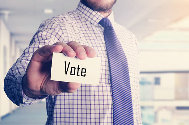 istock businessman in office showing card with text: Vote 535455304
