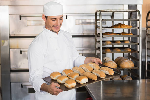 istock Happy baker showing tray of fresh bread 535456137