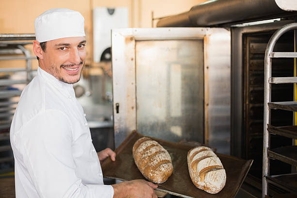 istock Happy baker holding tray of fresh bread 535456173