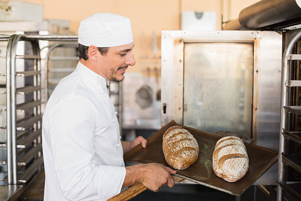 istock Happy baker holding tray of fresh bread 535456183