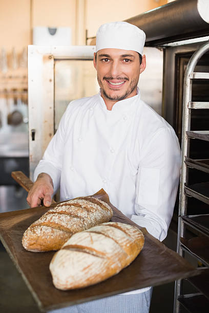 istock Happy baker holding tray of fresh bread 535456187