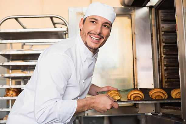 istock Happy baker taking out fresh croissants 535456461