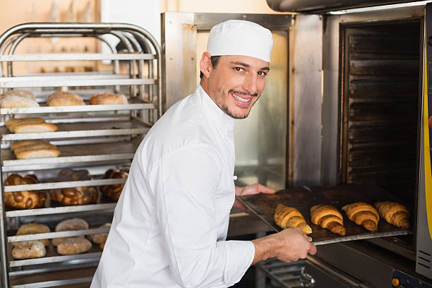 istock Happy baker taking out fresh croissants 535456463