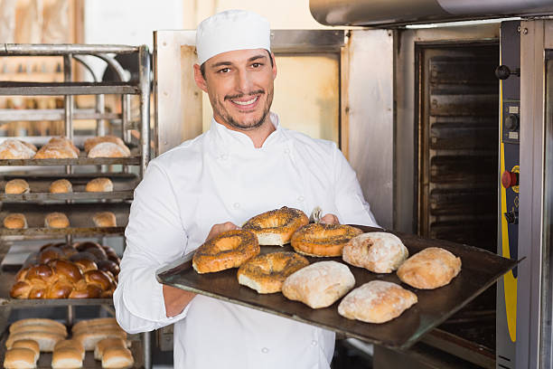 istock Happy baker showing tray of fresh bread 535456563