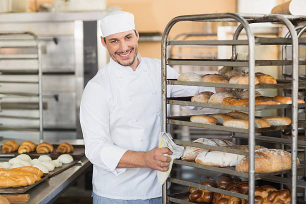 istock Smiling baker pushing tray of bread 535456781