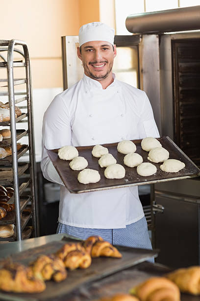 istock Smiling baker holding tray of raw dough 535457005