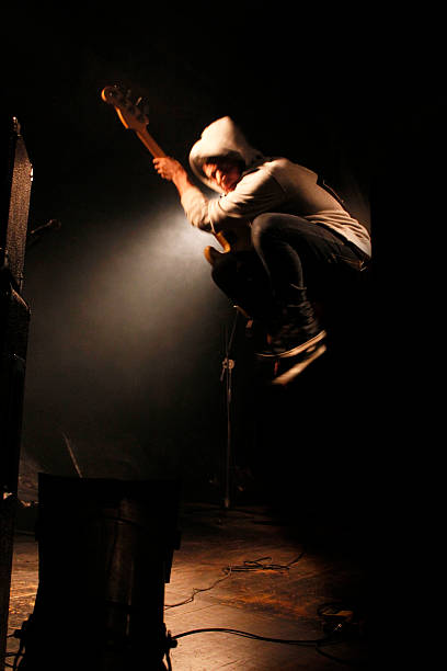 Jump on stage A young musician jumps on stage with his guitar during a live concert. rock musician photos stock pictures, royalty-free photos & images