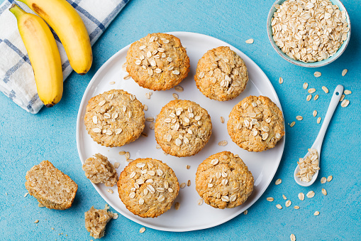 Healthy vegan oat muffins, apple and banana cakes on a white plate Blue stone background Top view