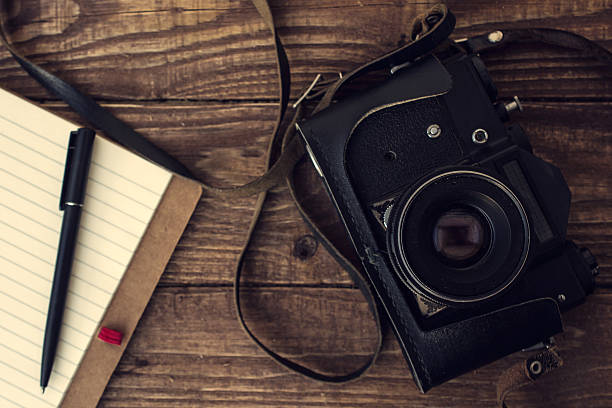 istock old retro camera with notebook and pen on wooden boards 535464440