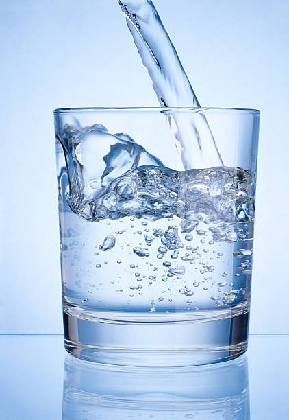 istock Pouring water into glass on blue background 535465009
