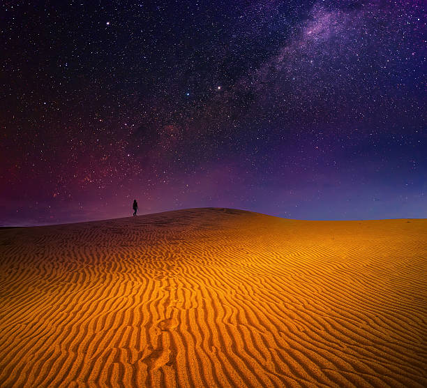 saccopelista si cammina tra le dune sabbiose sotto il cielo stellato - majestic landscape arid climate beach foto e immagini stock