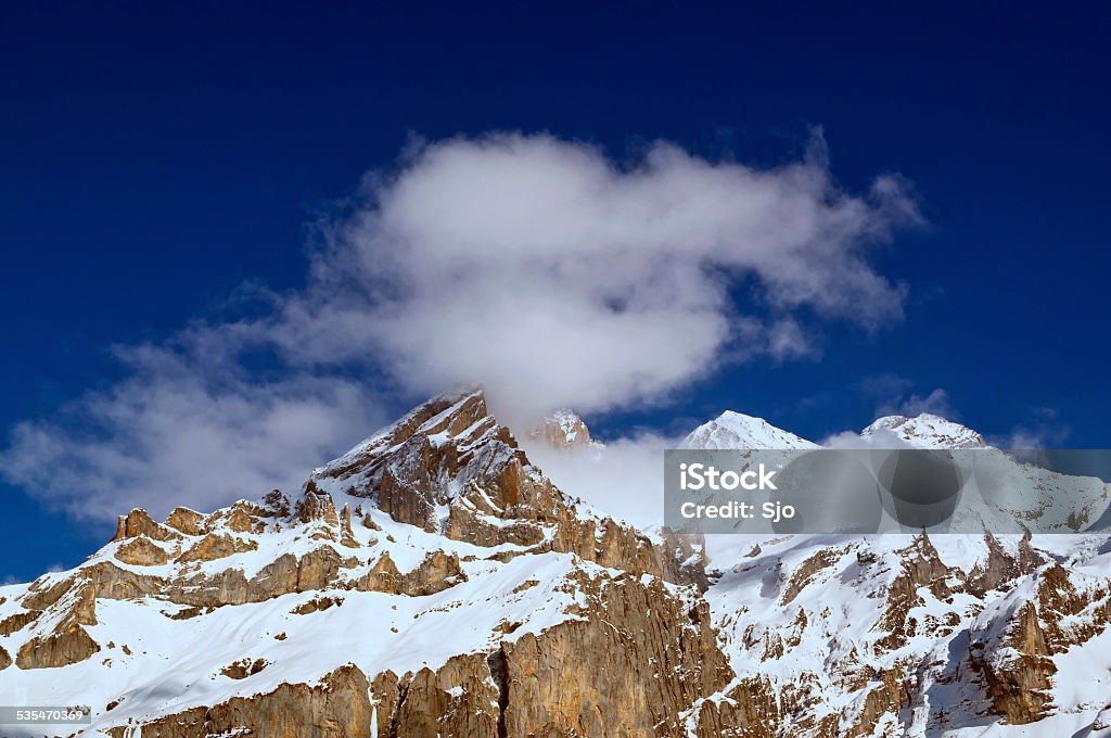 Swiss Alps mountain top Clouds hanging over a snowy mountain top in the Bernese Oberland in Switzerland on a beautiful winter day. Kandersteg Stock Photo
